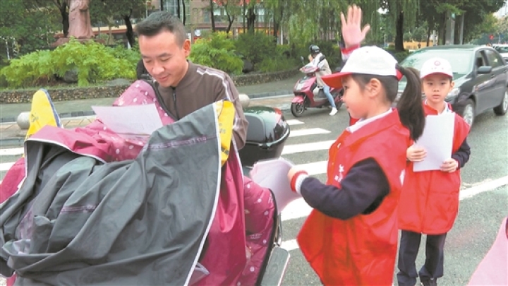 小小志愿者為過往行人和車輛發(fā)放文明出行宣傳單。.jpg